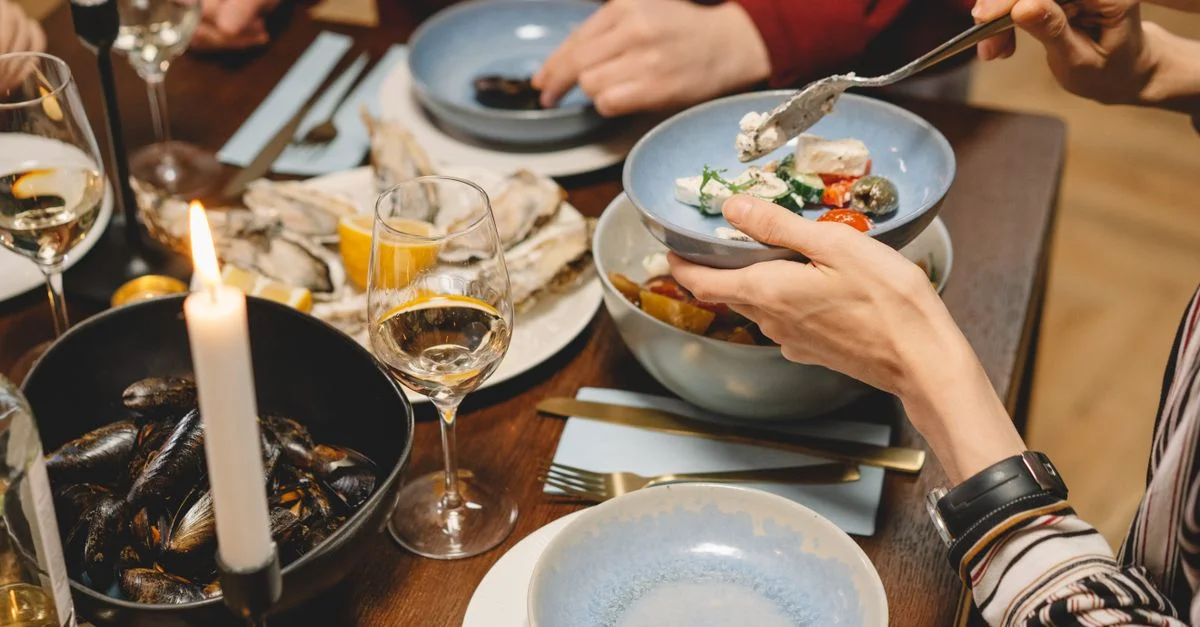 Un gros plan d'un dîner avec des fruits de mer, du vin et des bougies, créant une ambiance chaleureuse.