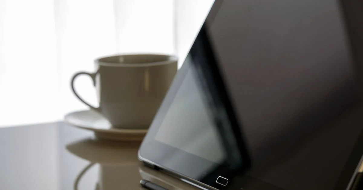 Tablette moderne et tasse à café sur un bureau réfléchi, parfait pour du contenu lié à la technologie.
